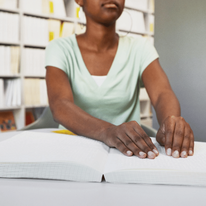 woman in a library reading a braille book