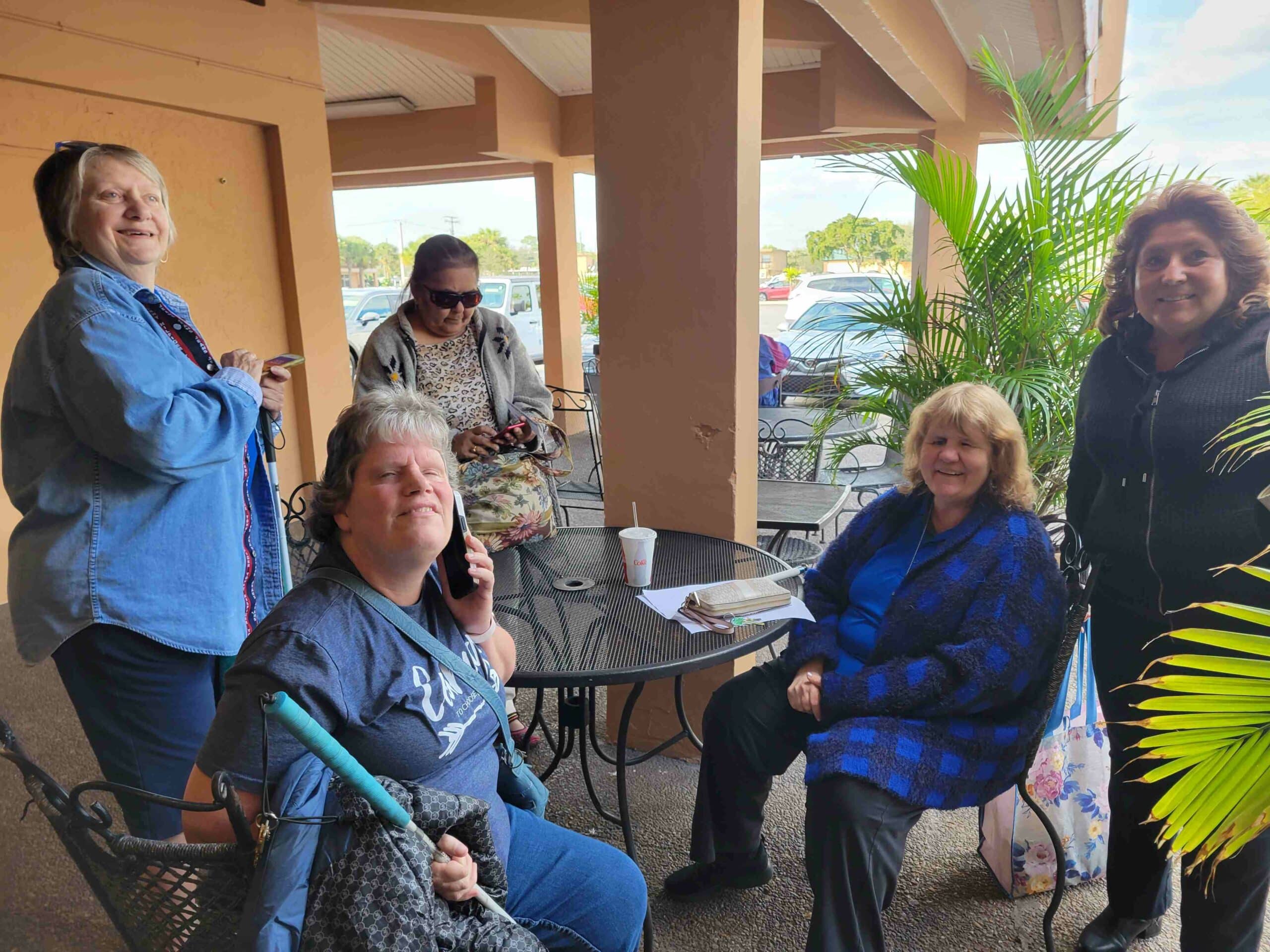 group of adults sit at table outside and smile at camera