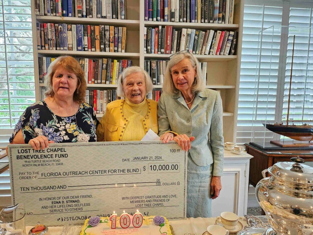 three women hold up large paper check for $10,000