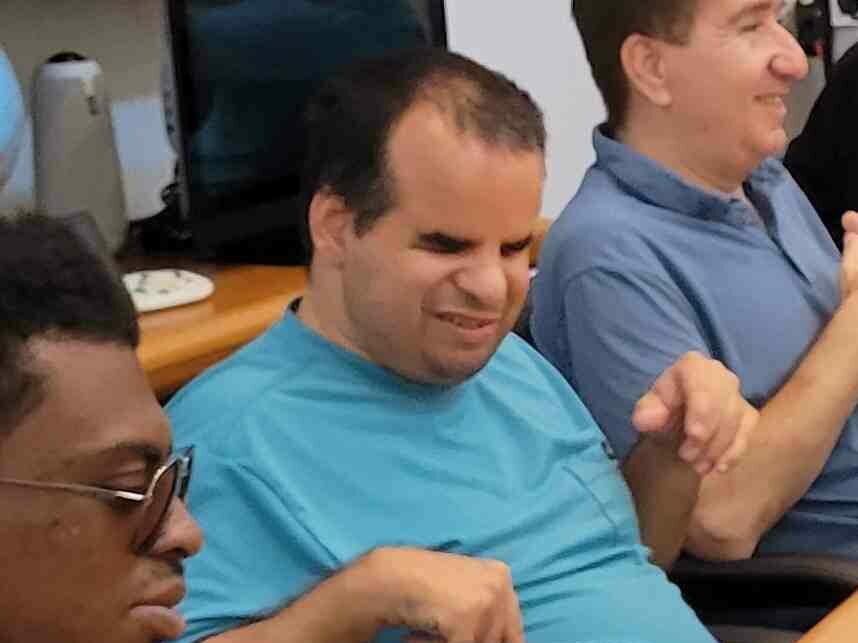 Man in blue shirt poses for camera with eyes closed