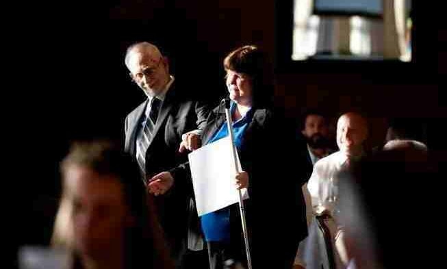 woman holding white cane and paper in other hand posing with man in suit