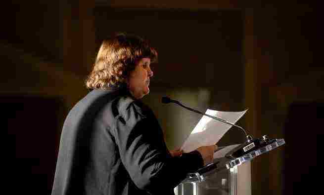Woman at podium speaking into microphopne