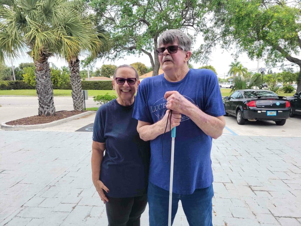 Man holding a white cane poses for picture with woman