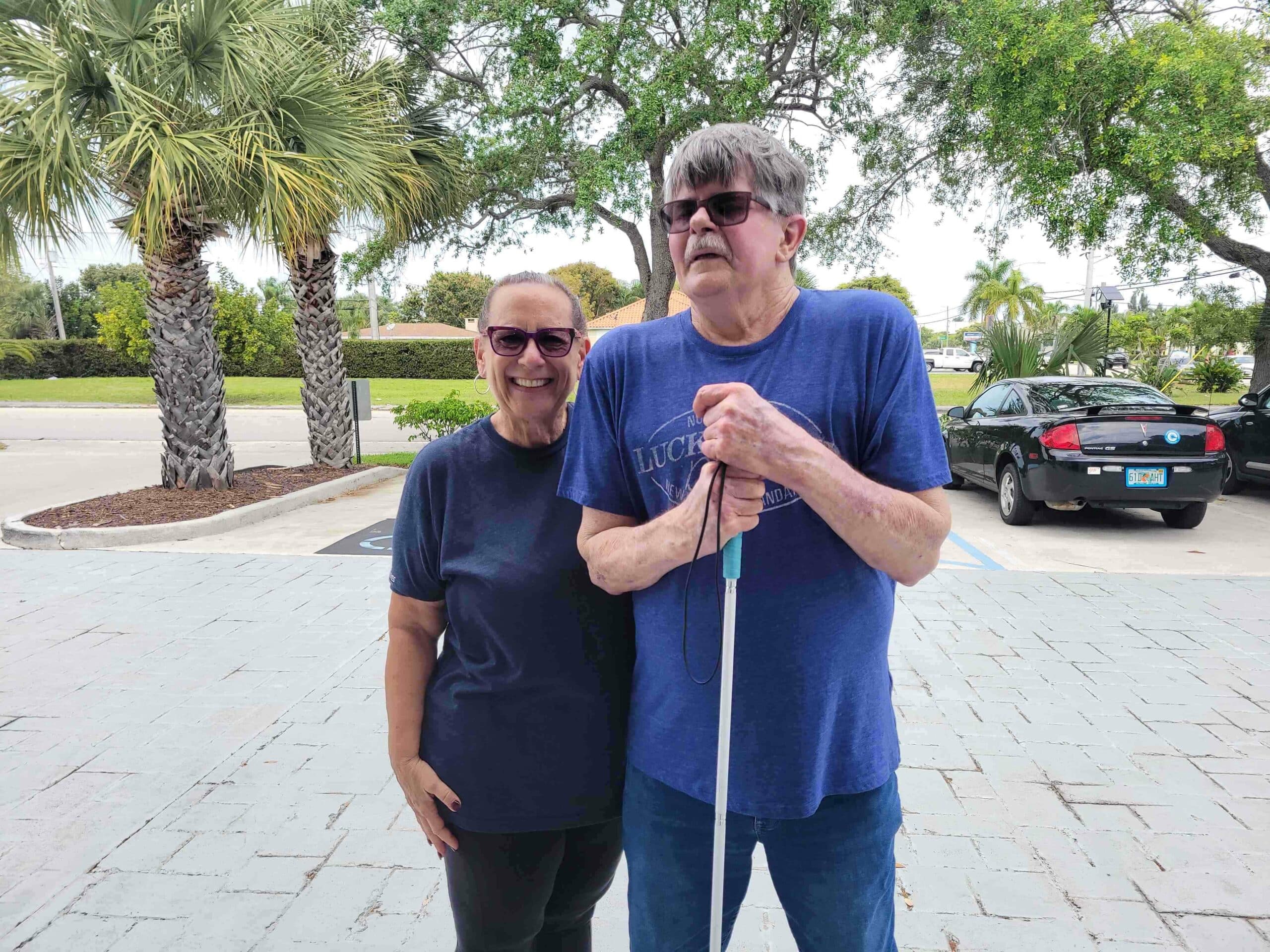 Man holding a white cane poses for picture with woman