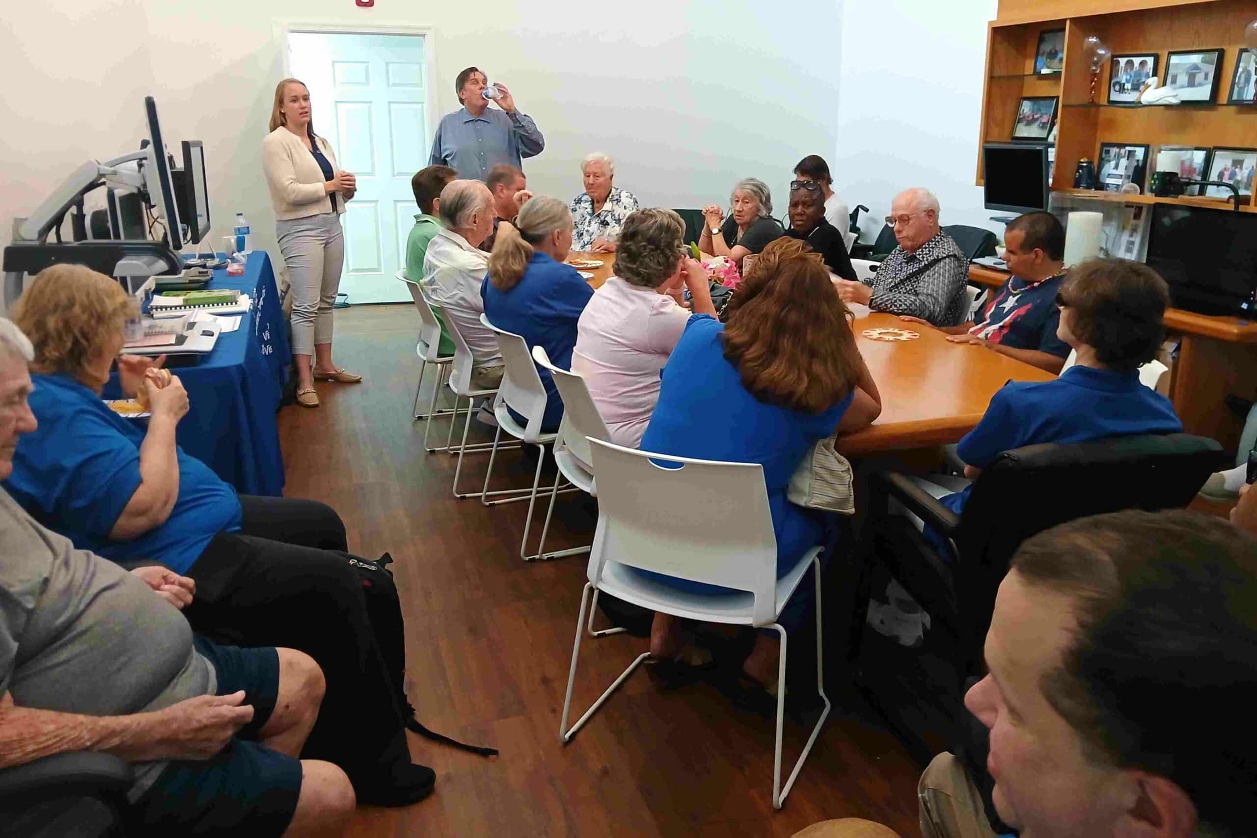 woman and man stand near a conference table full of adults