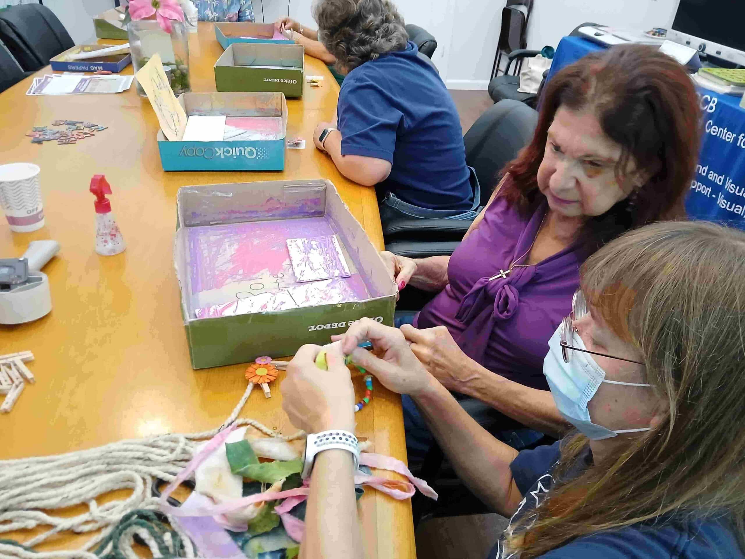 woman shows another woman how to do something with art supplies