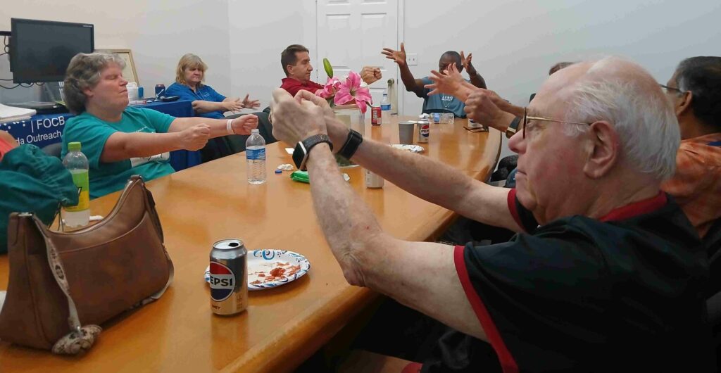 group of adults sit at table with hands raised in front of them