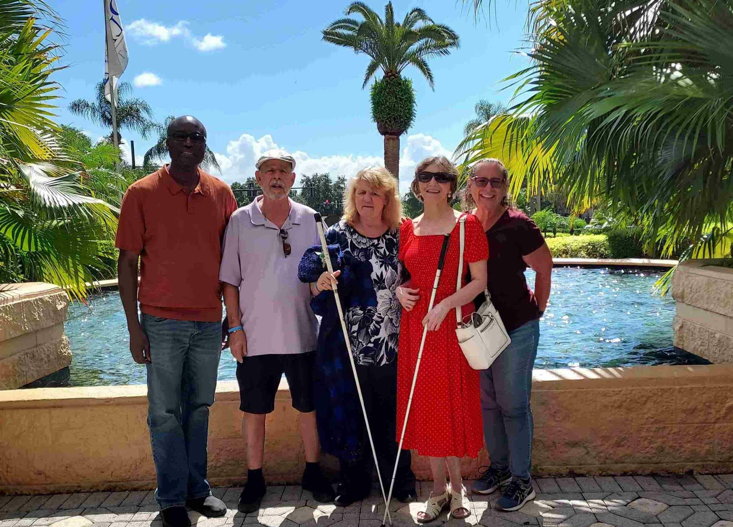5 adults standing in front of fountain with palm trees