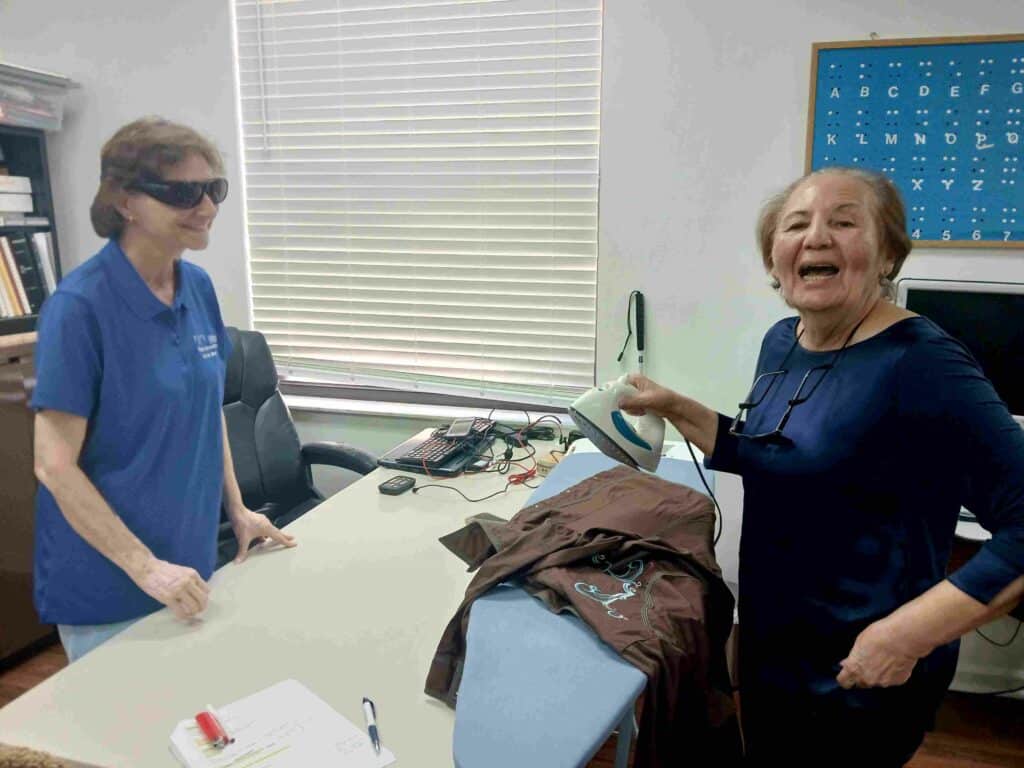 two women and an ironing board with iron smile for camera