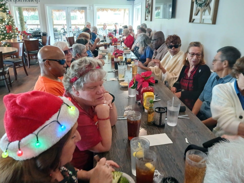 long narrow table with adults sitting on both sides in a restaurant