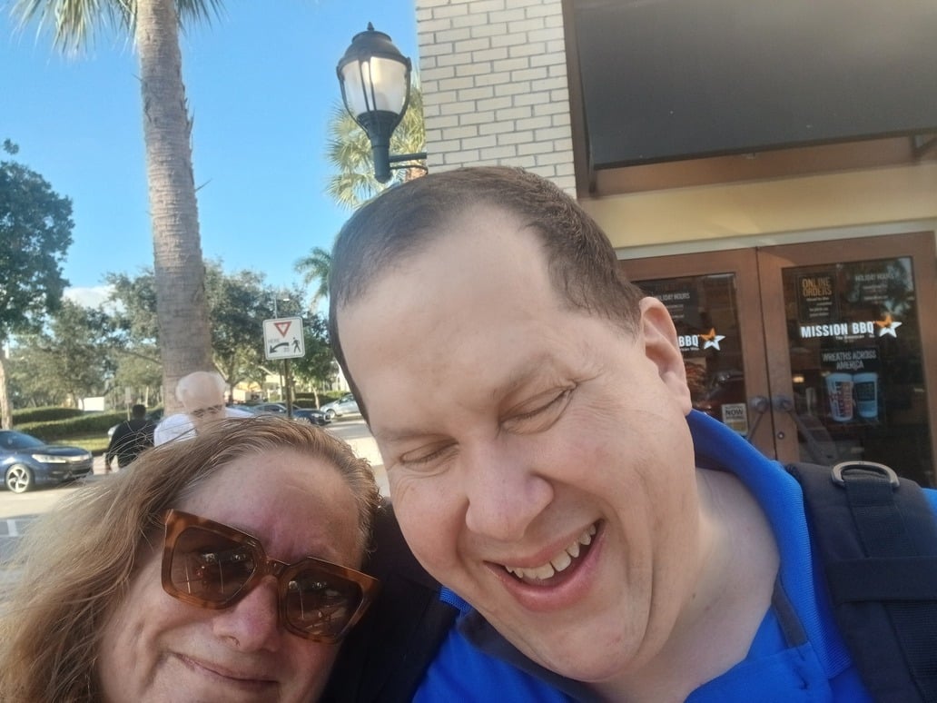 man and woman smile for a selfie outside of a restaurant