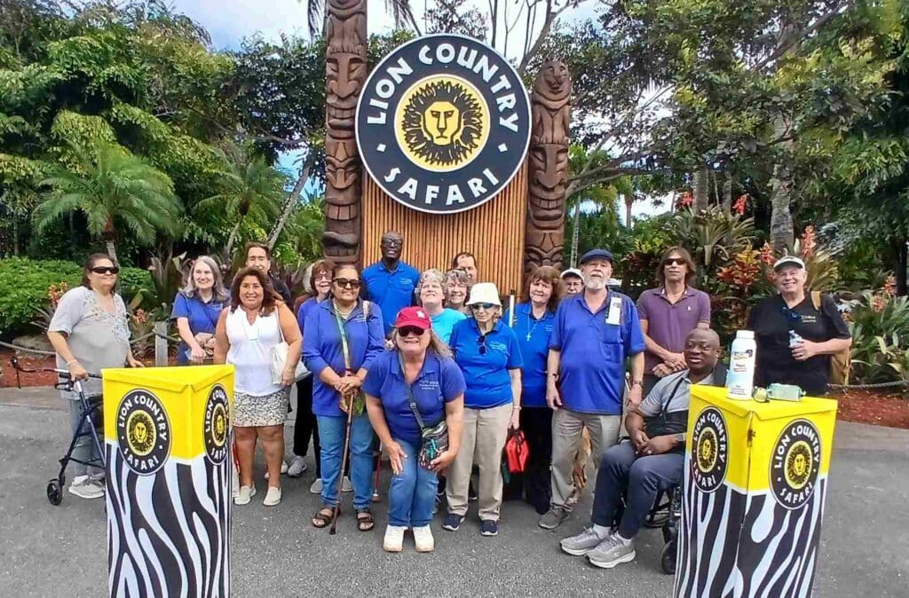 a group of adults stand together in front of the "Lion Country Safari" sign with a lion head