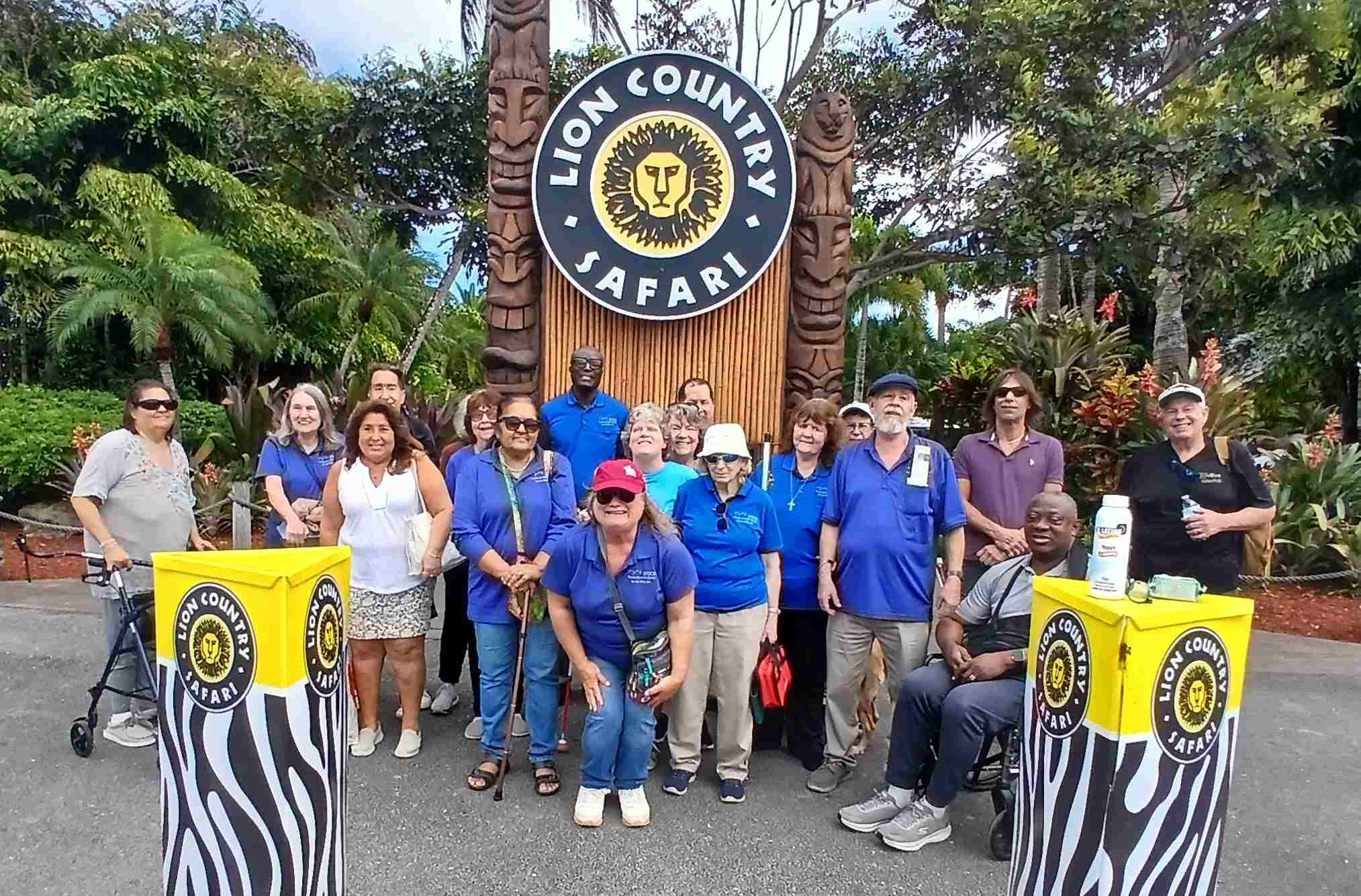 a group of adults stand together in front of the "Lion Country Safari" sign with a lion head