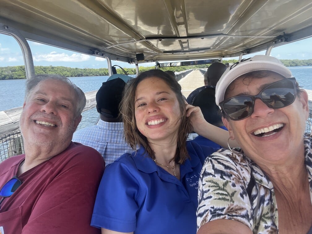 three adults pose for a selfie with water in the background