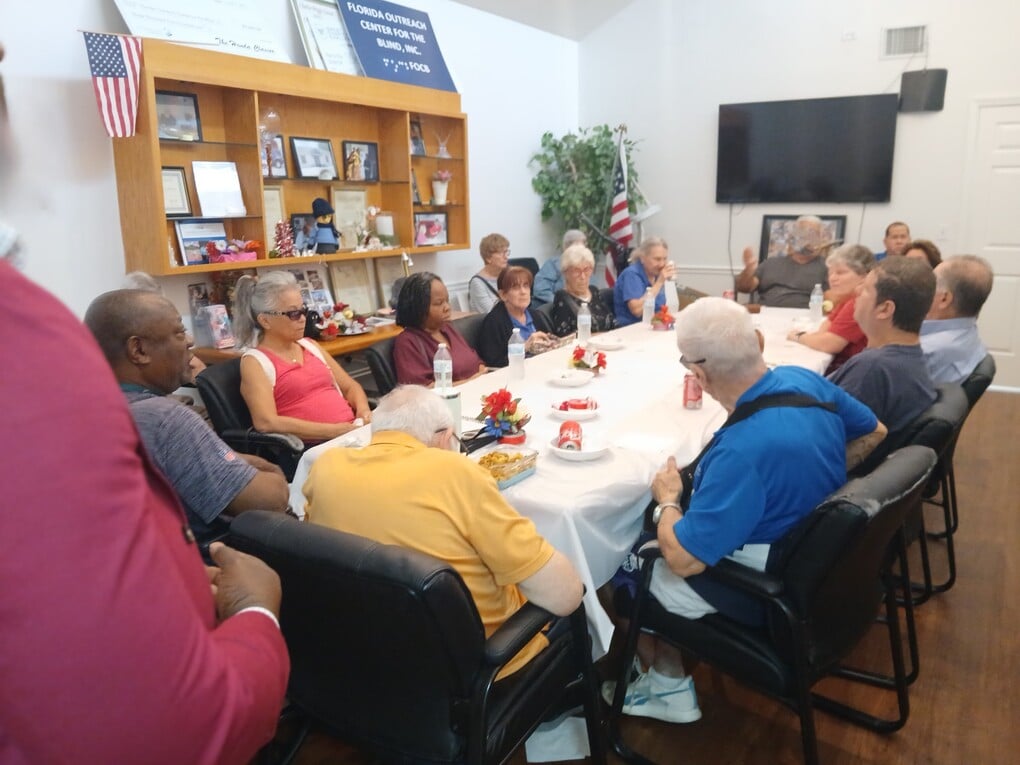 conference room full of people sitting around a white conference table