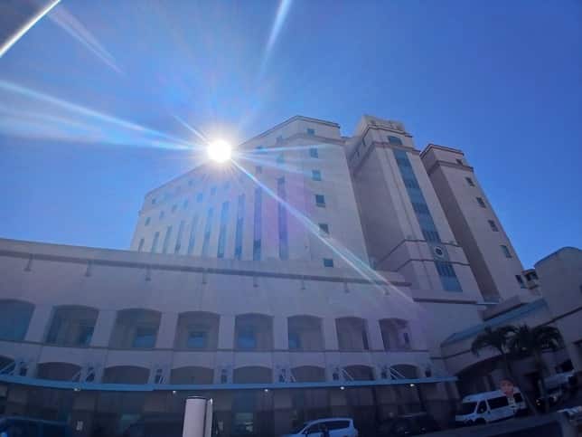 exterior image of a tall building with the sun shining and a blue sky