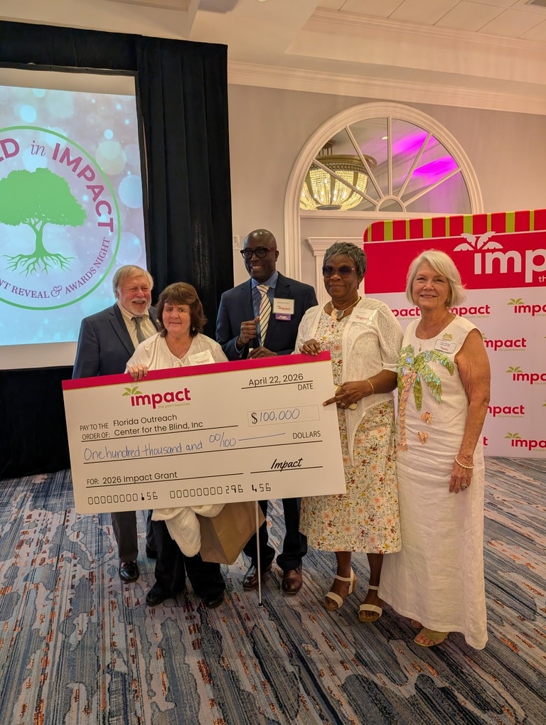 group of adults stand with over-sized check for $100,000