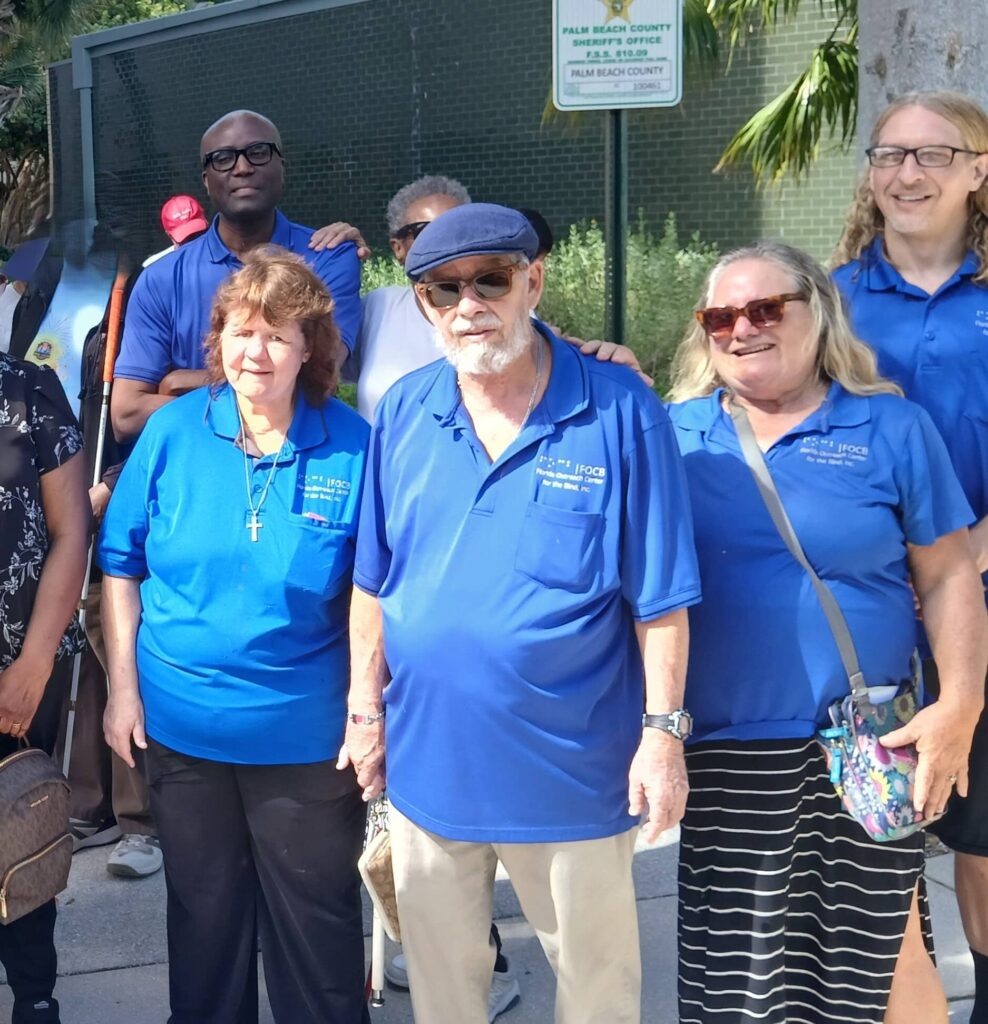 group of adults in blue polo shirts pose for picture outside