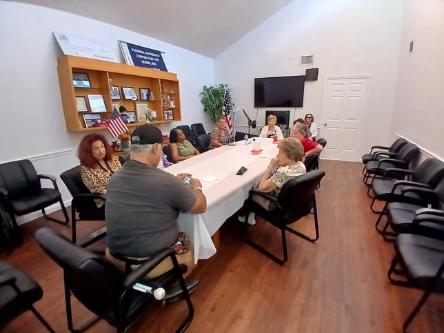 group of adults sit around a conference table with a white table cloth