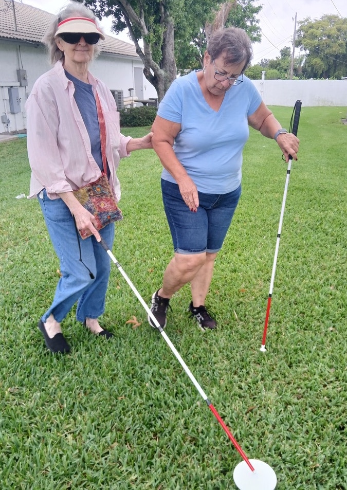two women outside in the grass white canes
