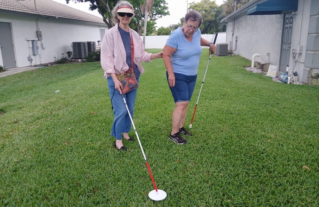 two women outside in the grass white canes