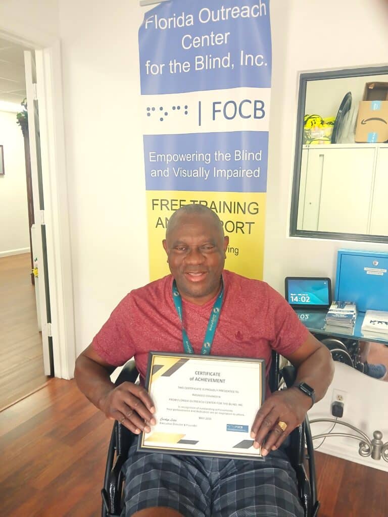 man in wheelchair holds up framed certificate