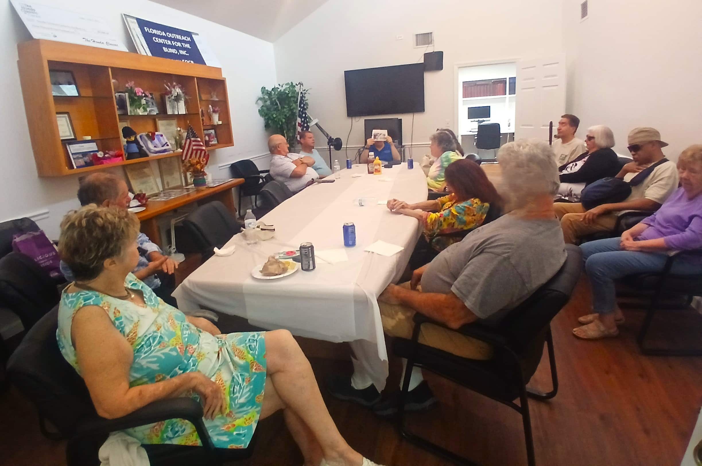 group of adults sit around a conference table with a white tablecloth