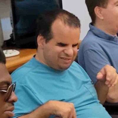 Man in blue shirt poses for camera with eyes closed
