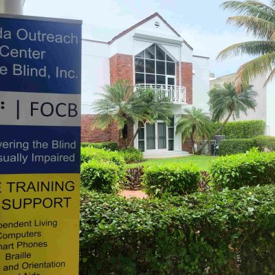 Exterior of the front of a building with a sign that reads, "Florida Outreach Center for the Blind"