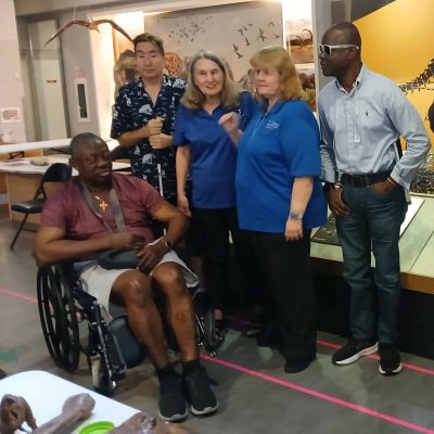 Four adults stand behind a man in a wheelchair