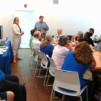 woman and man stand near a conference table full of adults