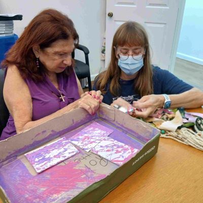 woman with box and marble art next to woman crafting
