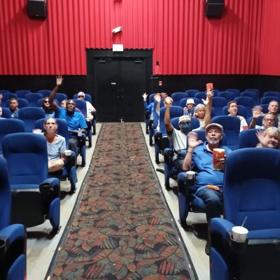 group of individuals sitting in a movie theatre with the lights on