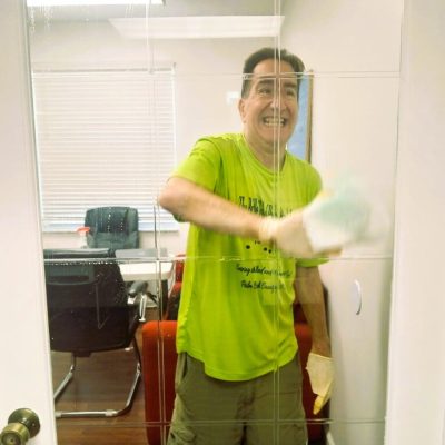 Man in green shirt cleaning a glass door