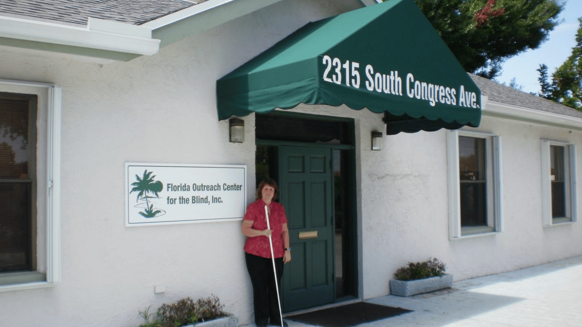 Executive Director, Carolyn Lapp standing by front door of Florida Outreach Center for the Blind