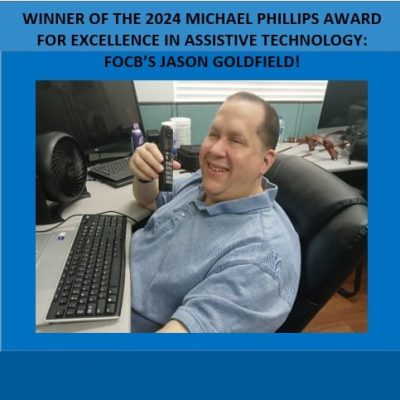 Man sits at computer holding phone