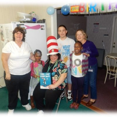 three children and staff enjoying Cat in the Hat book