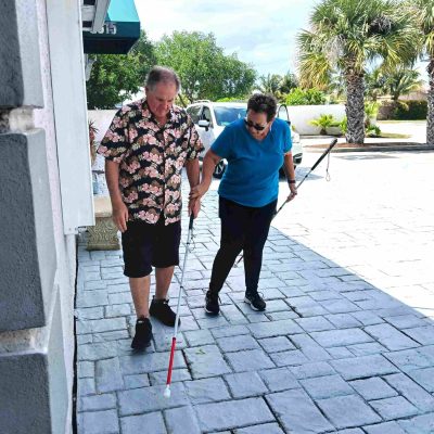 woman holds white cane showing man how to use it