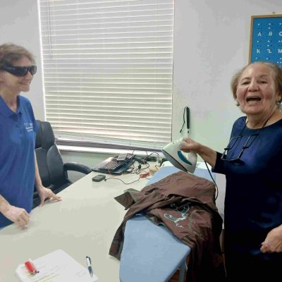 two women and an ironing board with iron smile for camera