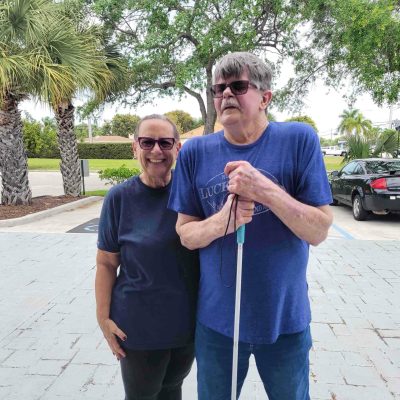 Man holding a white cane poses for picture with woman