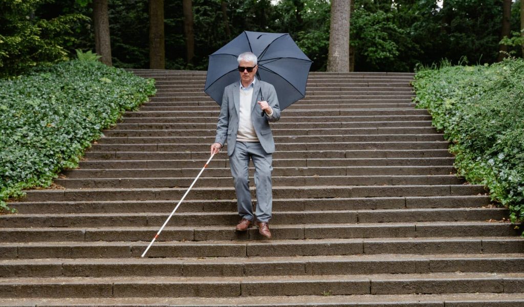 Senior walking down stairs with a white cane Senior walking down stairs with a white cane