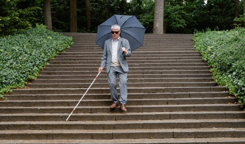 Senior walking down stairs with a white cane